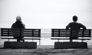 two people waiting on benches by the sea